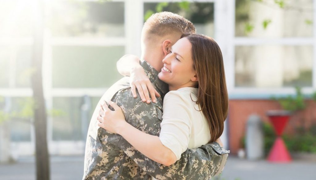 wife hugging army veteran.