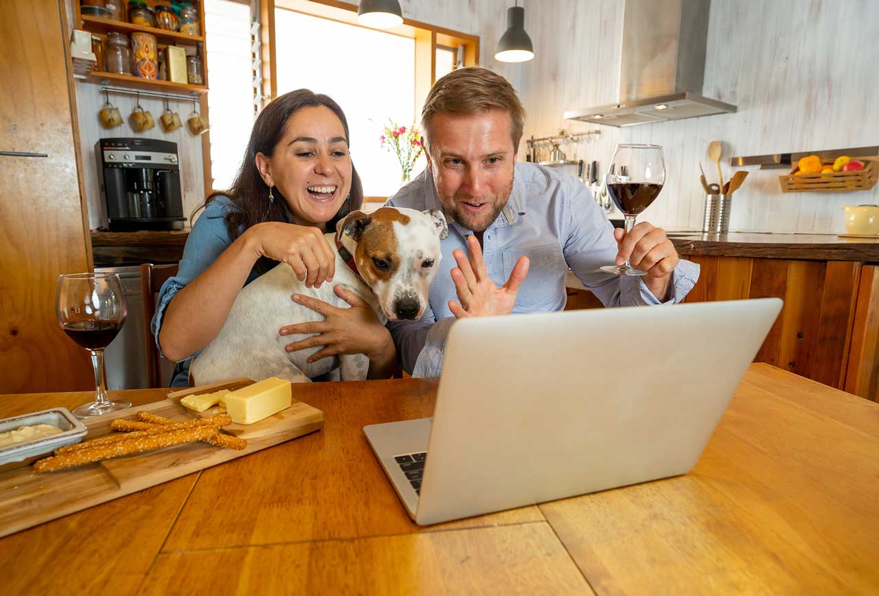 young couple with dog smiling and video chatting with grandparent in hospice care