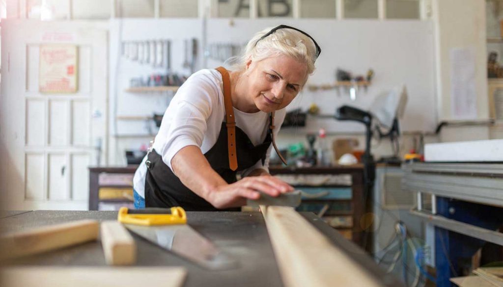 elderly woman starting a new hobby by woodworking in a workshop