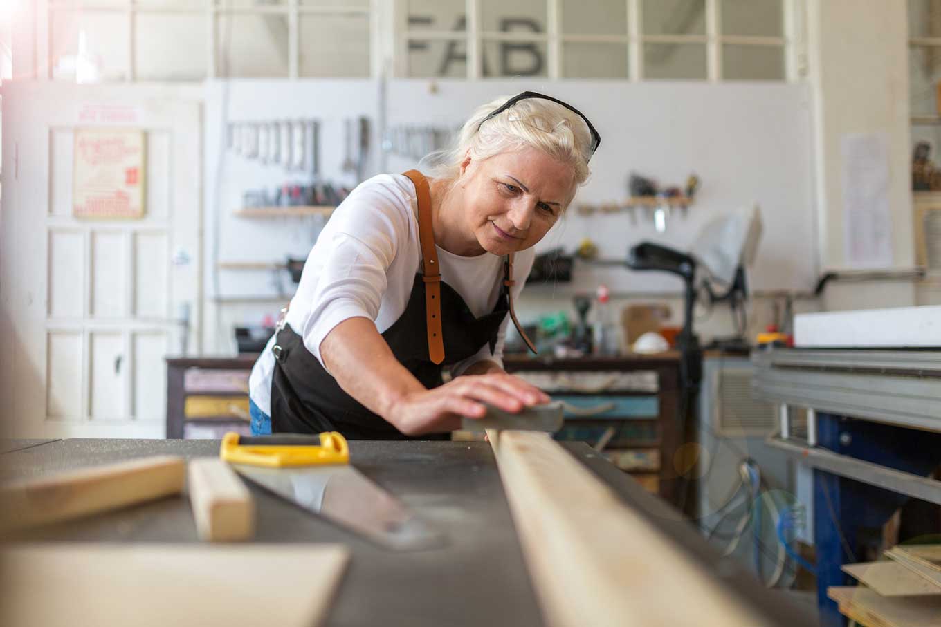 elderly woman starting a new hobby by woodworking in a workshop