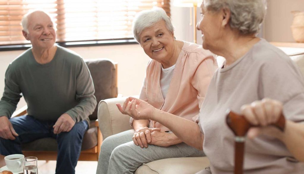 group of elderly people sitting and smiling together in hospice care